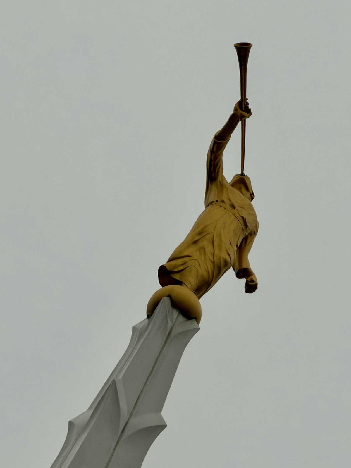 Golden statue on top of a church spire blowing a trumpet