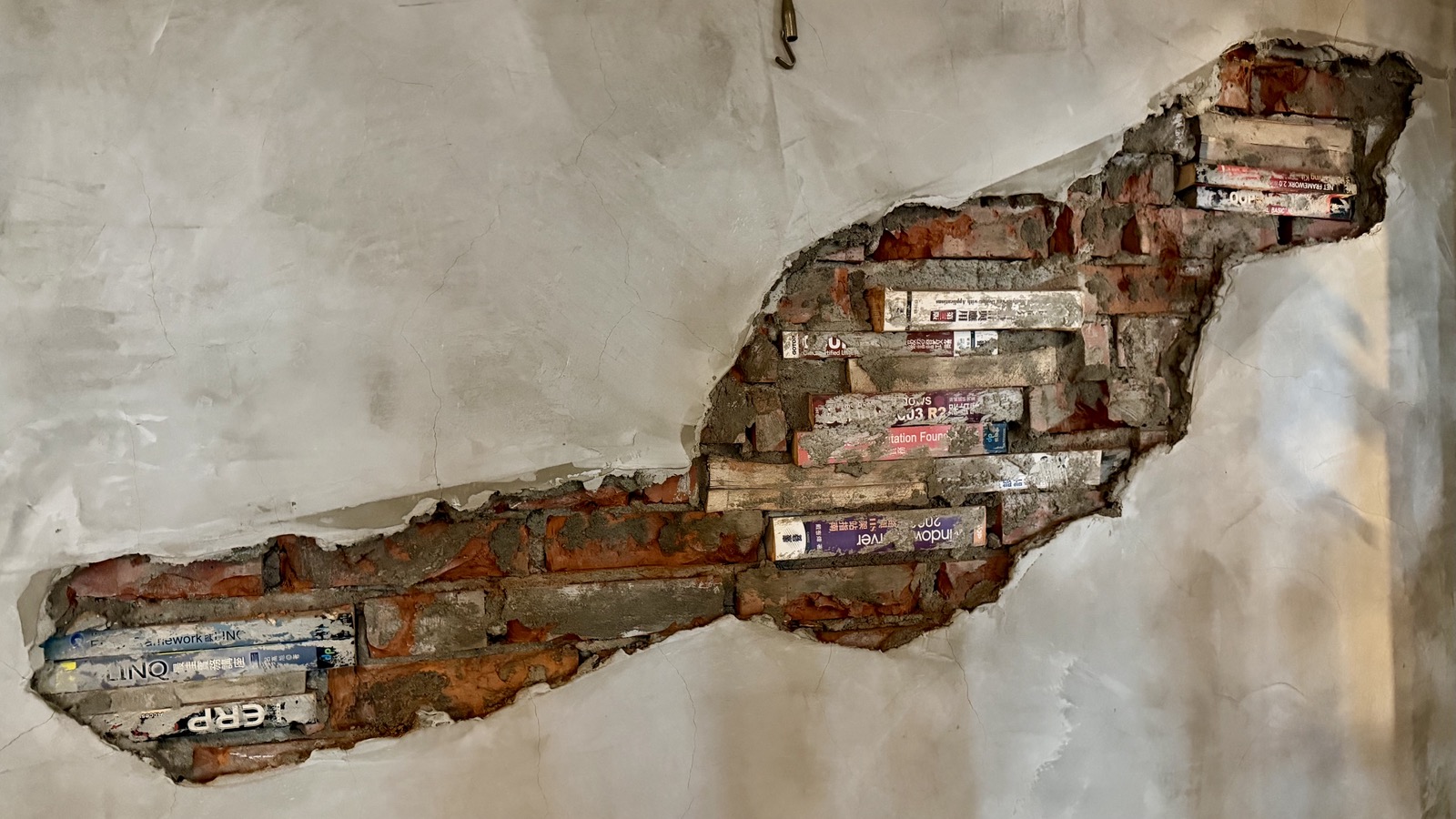 Part of an exposed brick wall, books mixed with bricks