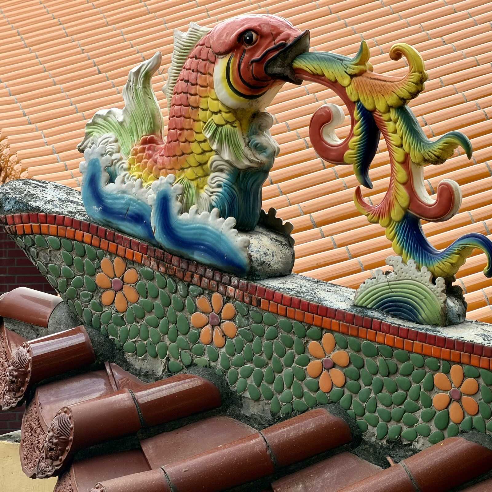 Fire-breathing multi-coloured fish on top of a temple